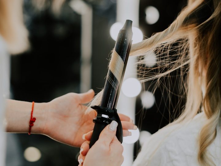 Eine Friseurin wickelt Locken mit einem Lockenstab